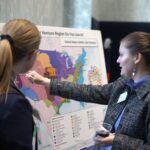 Two people put pins on a map showing the North American Joint Ventures